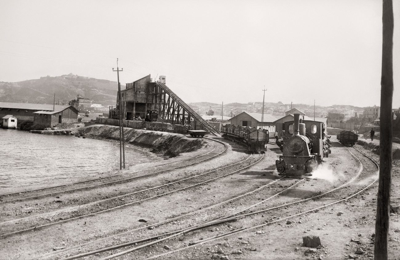 Fabrica de bloques prefabricados y locomotora de transporte de materiales, durante la construcción de los muelles de España y Cañonero Dato. Ceuta, 1925<br/>Gelatina de plata / Silver gelatin